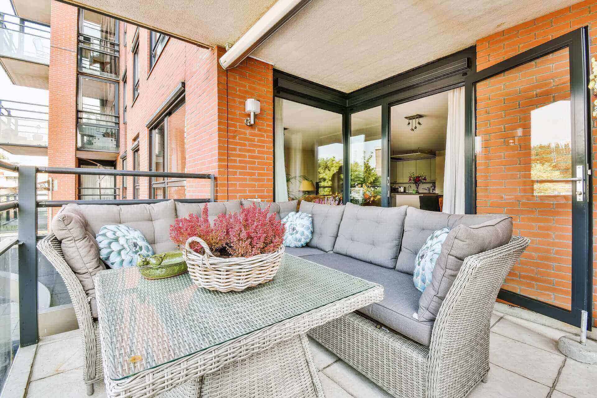 Covered balcony lounge with wicker seating and city views